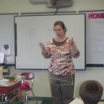 Mrs. Atkinson showing the class you can hear sound better through a solid.