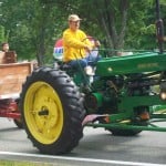 Farm tractor pulling hey wagon with people.